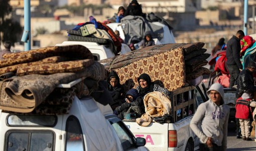 Människor sitter på flakbilar och återvänder till Syrien.