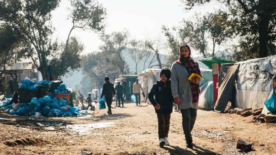 En asylsökande mamma och hennes son går genom lägret Moria på den grekiska ön Lesbos.