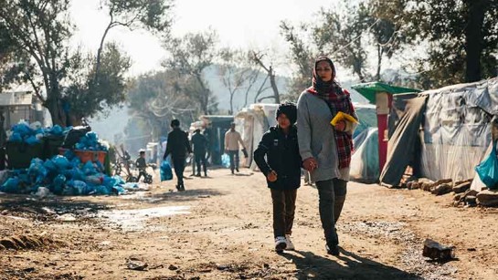En asylsökande mamma och hennes son går genom lägret Moria på den grekiska ön Lesbos.