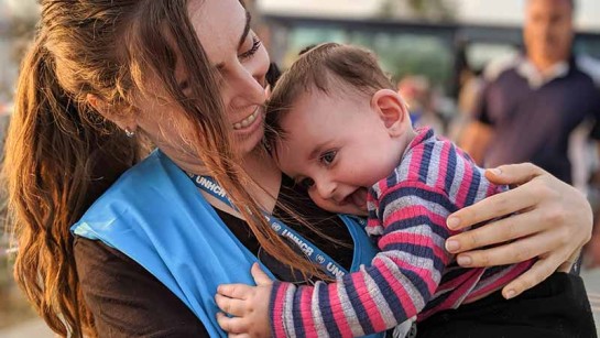 Vår kollega Shang hjälper familjer på flykt att bära sina små barn till en skyddad plats i Dohuk i Irak.