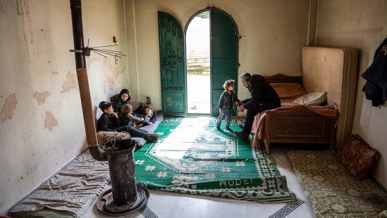 Ahmad och hans fru Salima sitter tillsammans med sina bar i rummet där de bor utanför Aleppo i Syrien. Familjer har varit på flykt sedan 2012.