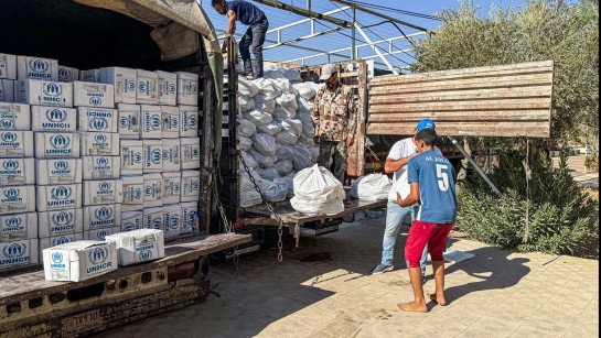 Två personer lämnar ut nödpaket från UNHCR.