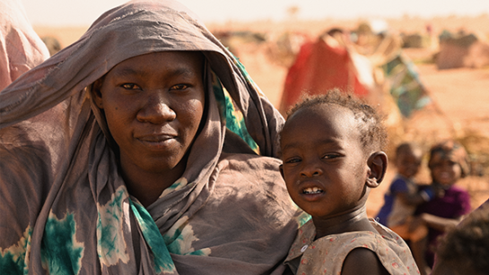 En kvinna håller sitt barn i famnen vid gränsen mellan Sudan och Tchad
