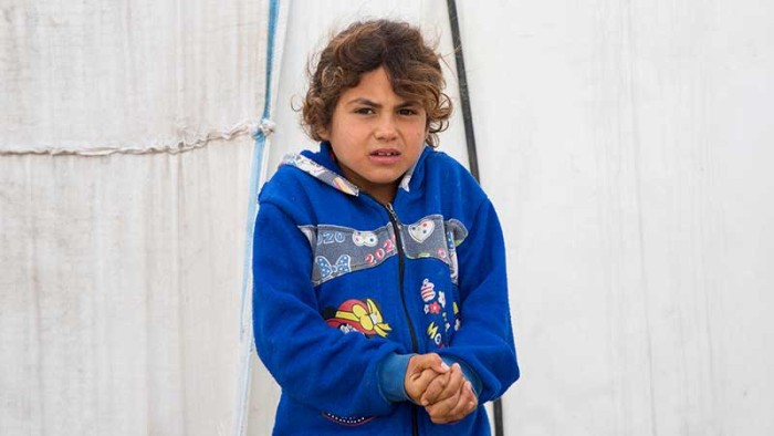 En flicka står utanför sitt tält mitt i vintern.