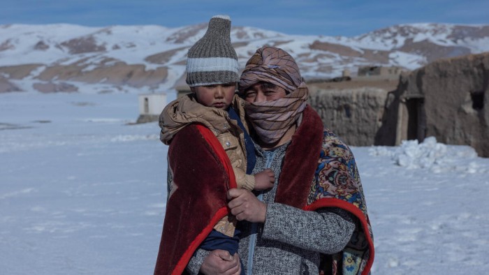 En bild på en vuxen och ett barn i Afghanistan. Det är snöigt och ser kallt ut.